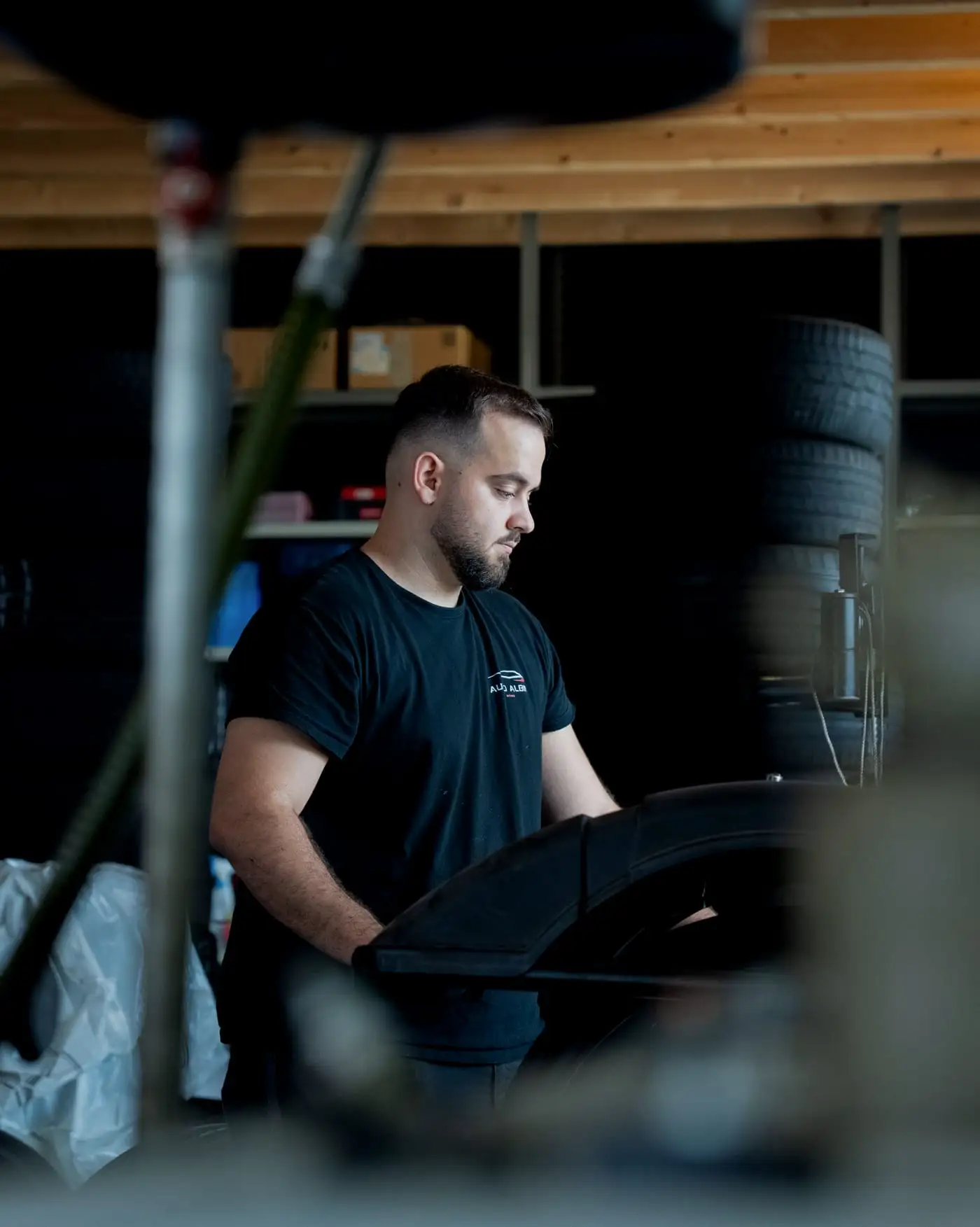 Mechaniker im Auto-Albin-Shirt arbeitet konzentriert an einer Maschine in der Werkstatt
