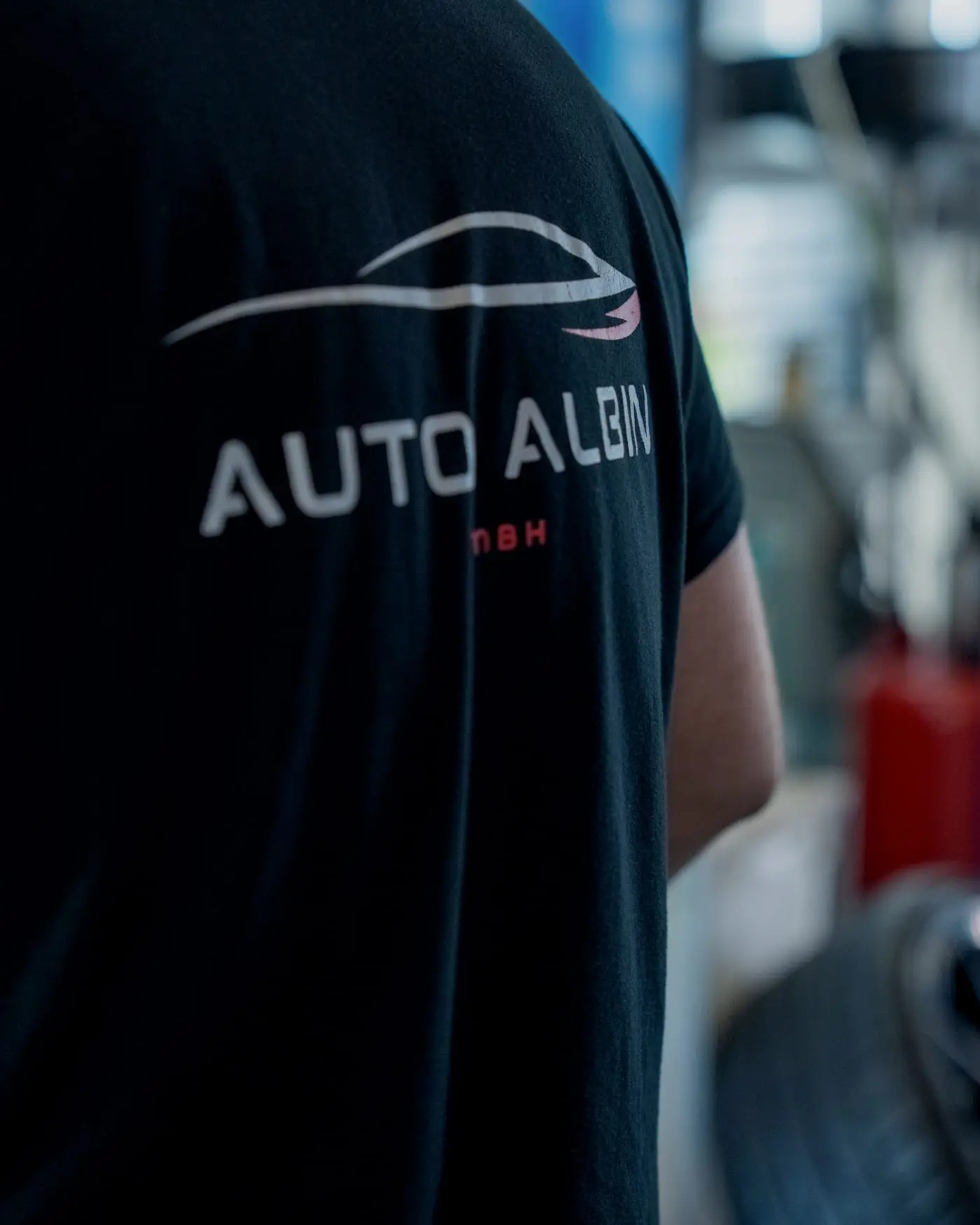 Rücken im schwarzen Arbeitsshirt mit dem Logo von Auto Albin