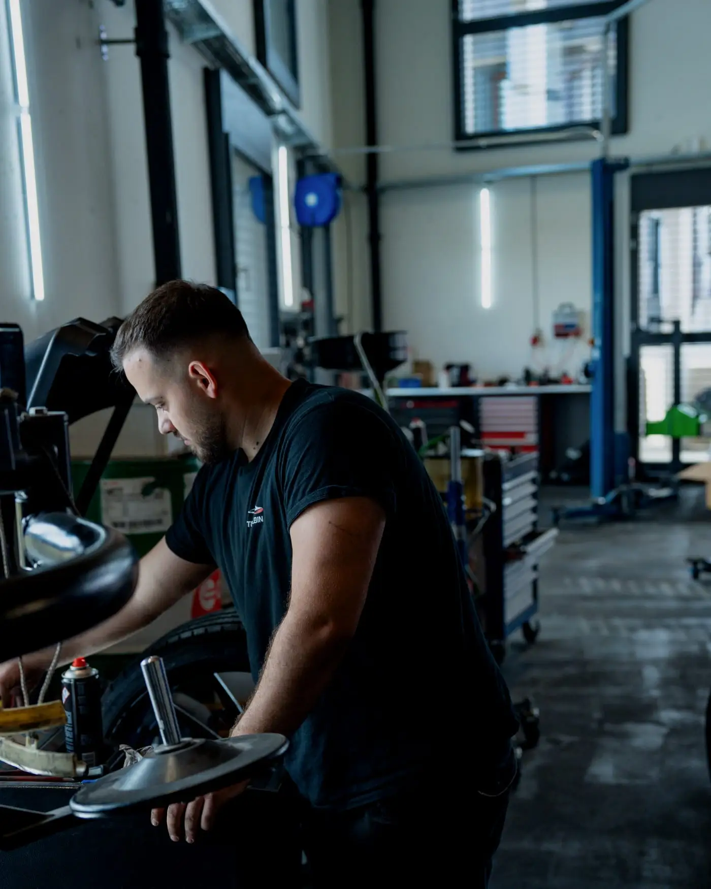 Mechaniker an der Reifenmontiermaschine in der hellen Werkstatthalle