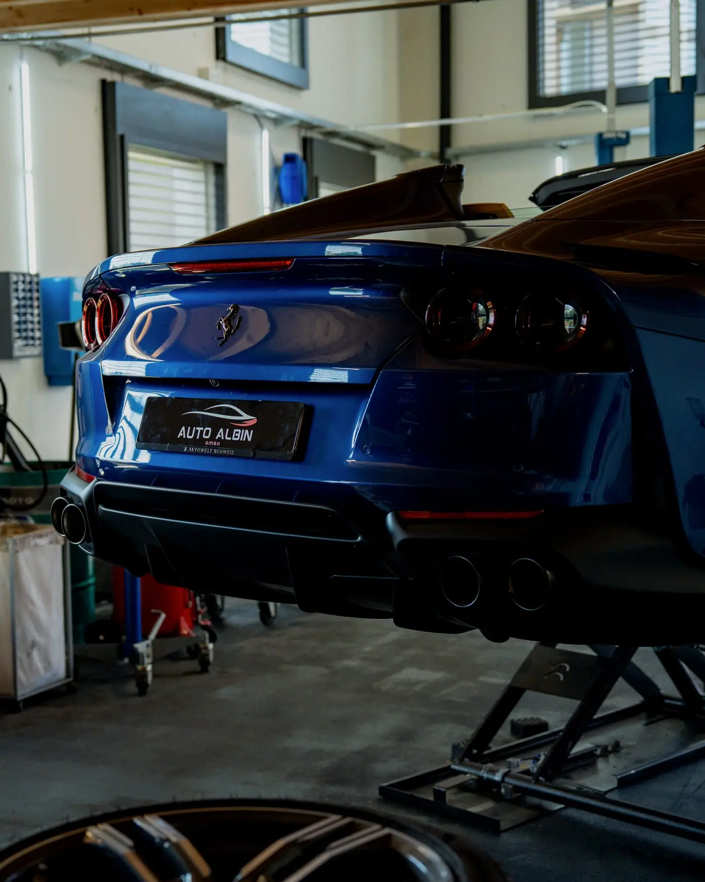 Blauer Sportwagen von hinten auf der Hebebühne in der Halle