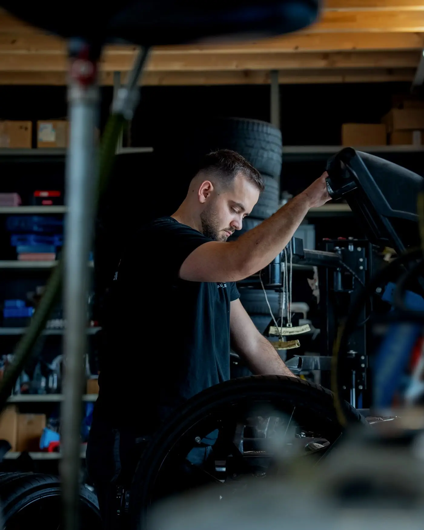 Mechaniker an der Maschine, im Hintergrund Reifenregale der Werkstatt