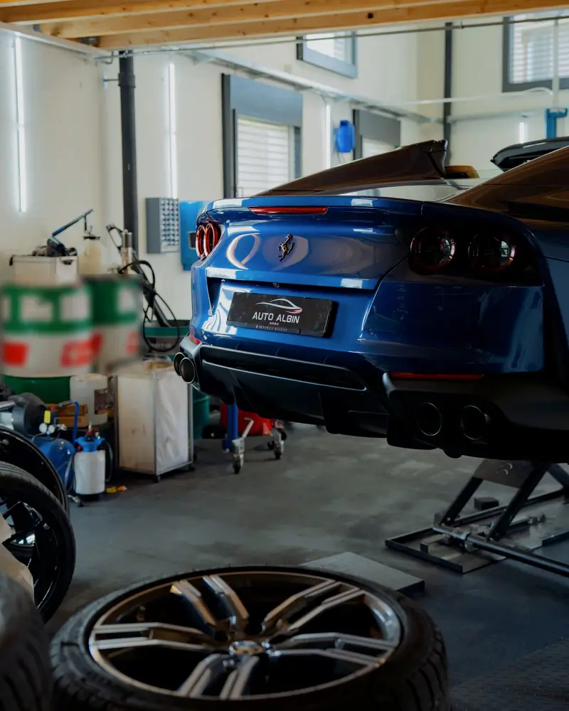 Blauer Sportwagen von hinten auf der Hebebühne in der Werkstatt von Auto Albin in Sins AG, davor ein Rad